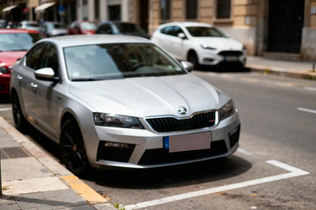 Voiture grise garée sur la rue avec d'autres véhicules en arrière-plan flou.