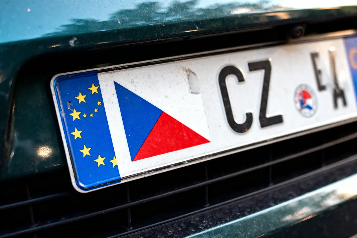 Plaque d'immatriculation tchèque européenne sur voiture verte, lettres "CZ", drapeau tchèque visible.