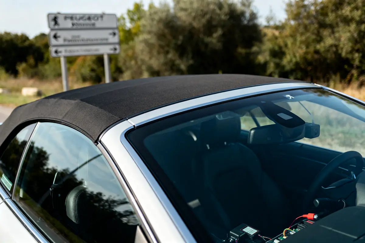 Voiture cabriolet Peugeot 308cc stationnée devant des panneaux routiers en campagne