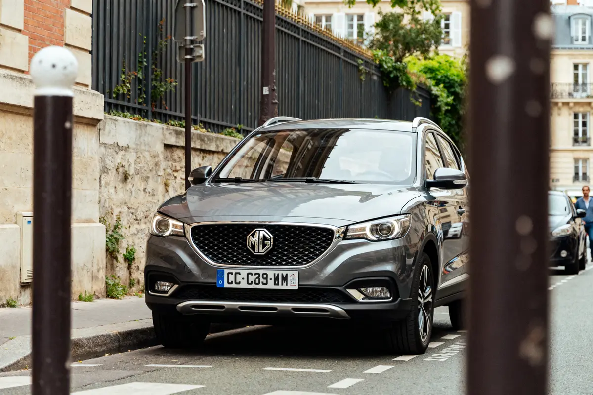 SUV MG ZS gris stationné dans une rue urbaine avec bâtiments en arrière-plan