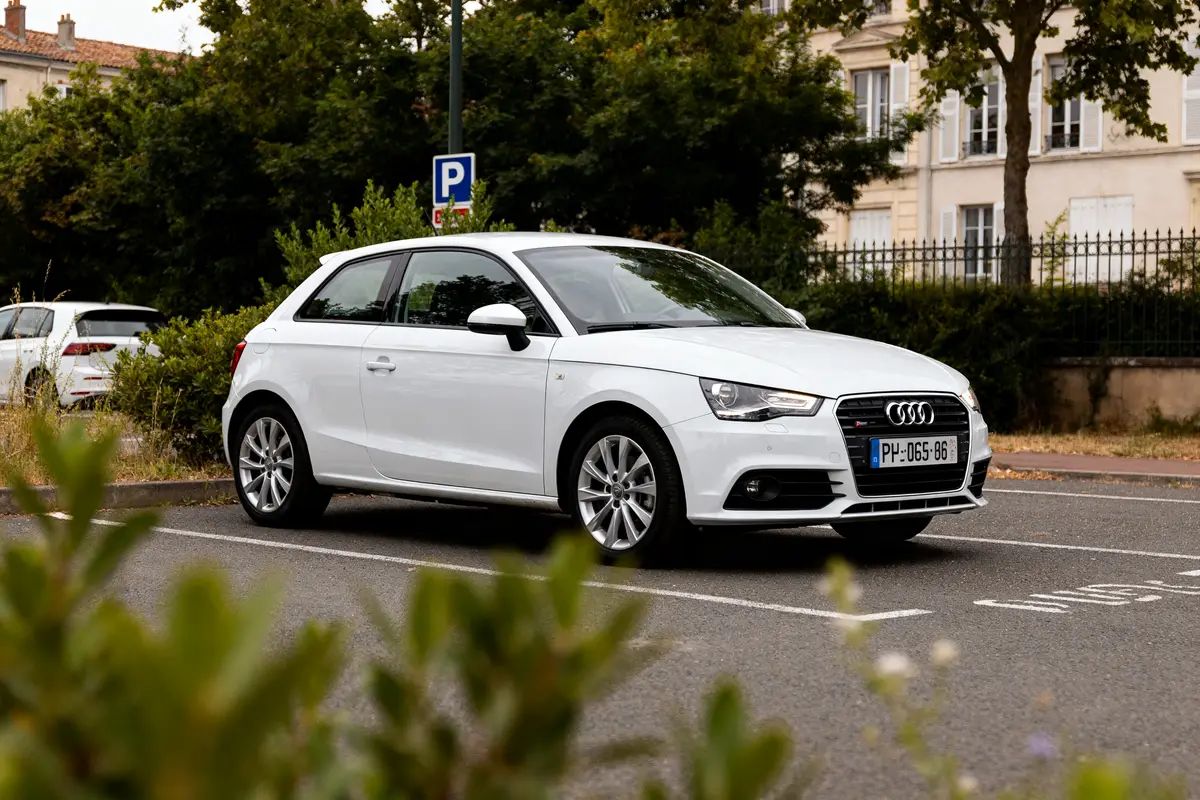 Voiture Audi A1 blanche stationnée, audi a1 occasion en milieu urbain verdoyant