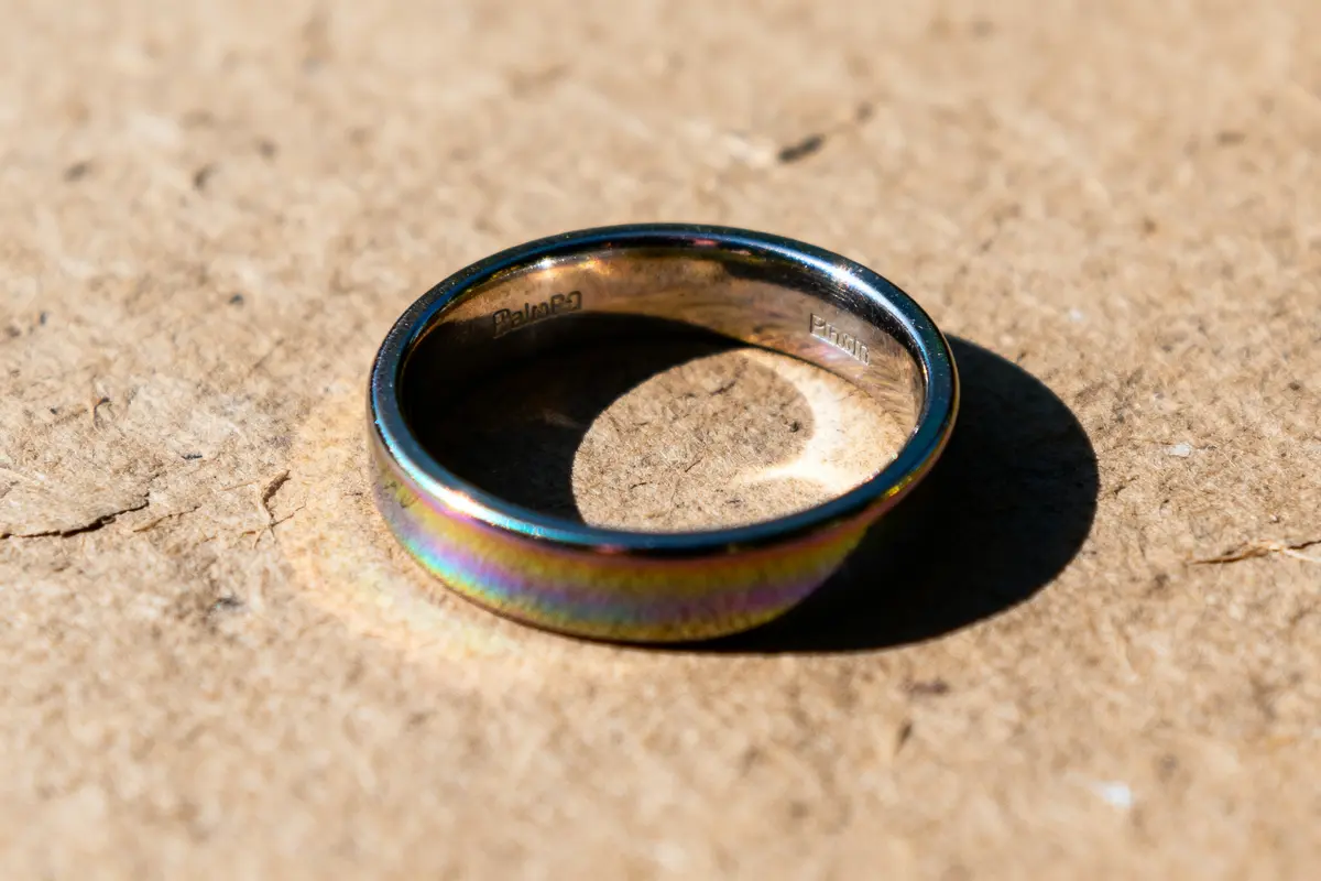 Bague irisée en métal sur fond brun avec reflets comme bougie en iridium