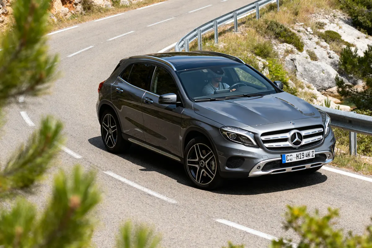 Mercedes GLA grise conduite sur route sinueuse entourée de végétation et rochers