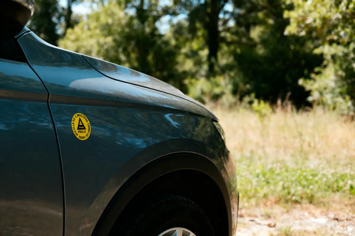 Voiture bleue avec autocollant jaune, synergie Eurodatacar, dans un environnement boisé et ensoléillé