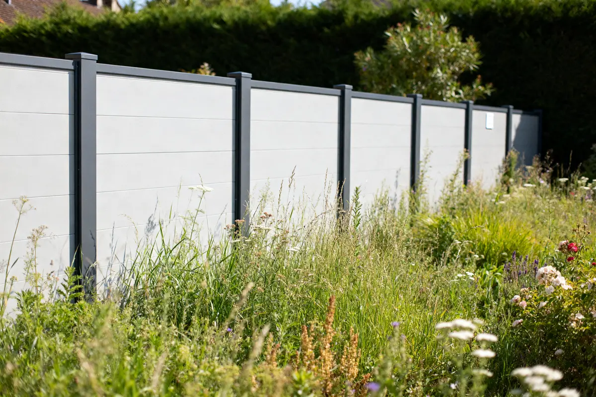 ClĂ´ture moderne avec jardin fleuri et verdoyant en avant-plan