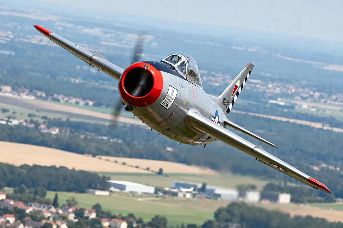 Avion de chasse en vol aérodynamique surplombant le paysage, modèle F-86F Sabre.