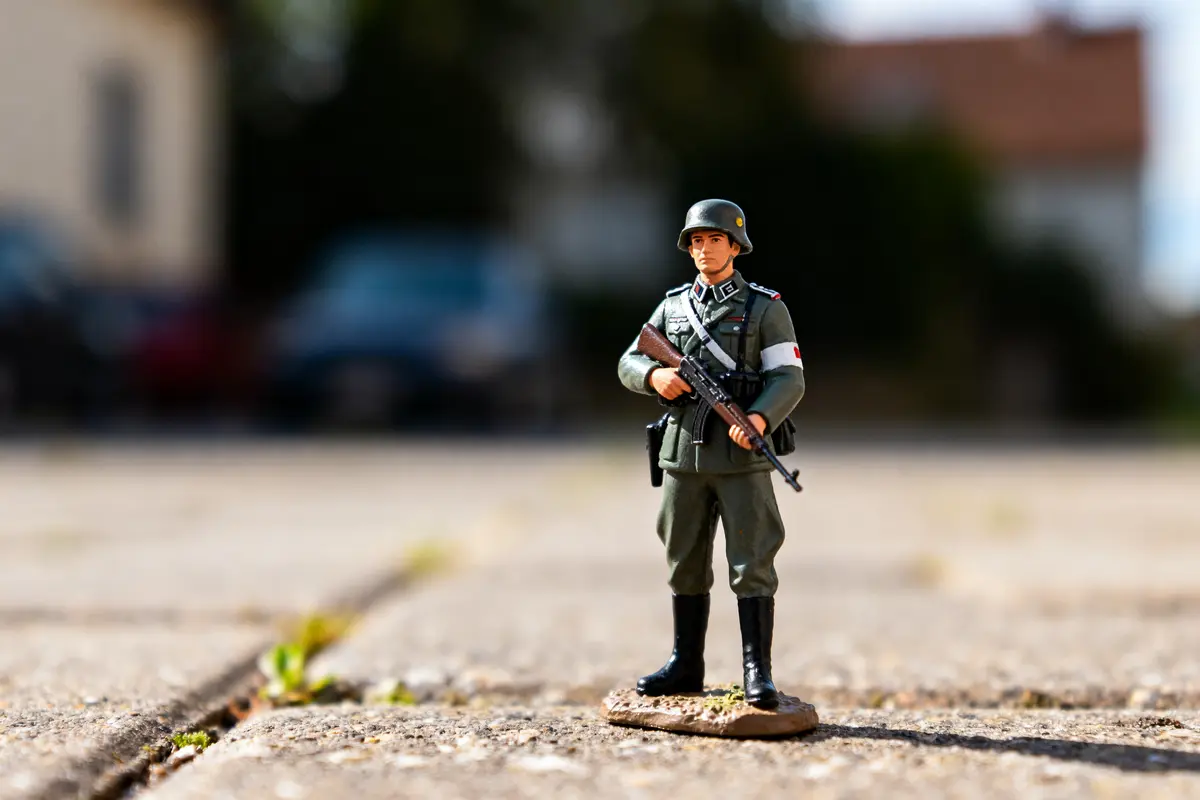 Figurine soldat en uniforme militaire avec fusil sur sol extérieur en béton