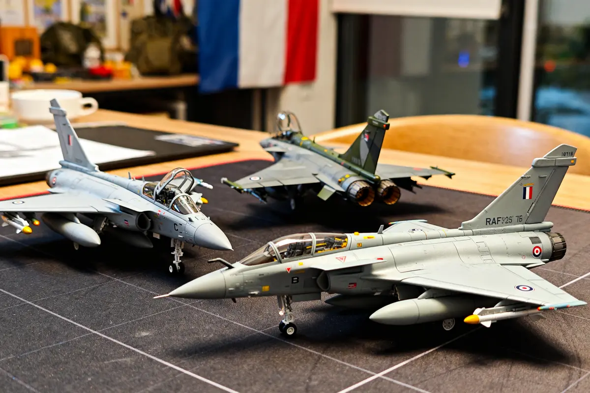 Trois maquettes de chasseurs Rafale alignées sur une table de modélisme détaillée